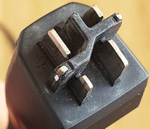 Close-up van de zwarte steker van een Bosch-lader voor het smart system, met vier metalen contactpennen in een kruisvormige houder