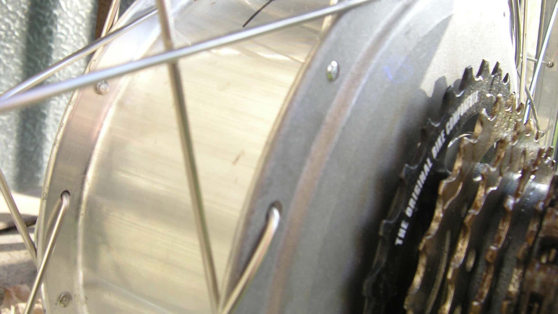 Close-up van een oudere achternaafmotor tussen de spaken van een achterwiel, met een cassette ernaast (geen Bosch Hub Line)