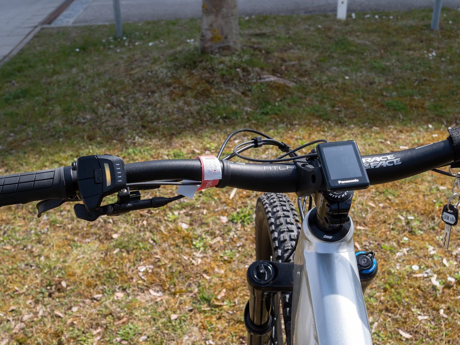 Stuur van een elektrische mountainbike met links de bedieningsknop en rechts het kleine Panasonic-display waarop de ondersteuningsstand wordt gekozen