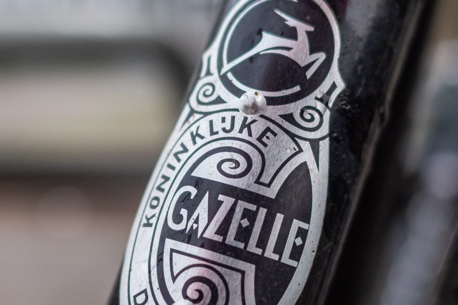 Close-up van het klassieke Koninklijke Gazelle-balhoofdplaatje met gazelle-logo op een zwart fietsframe (geen Gazelle Curb)