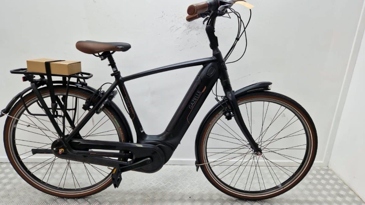 Gazelle Grenoble elektrische stadsfiets in mat zwart met hoge instap, Bosch-middenmotor bij de trapas, accu weggewerkt in de onderbuis, bruin zadel en bruine handvatten, banden met bruine zijwand