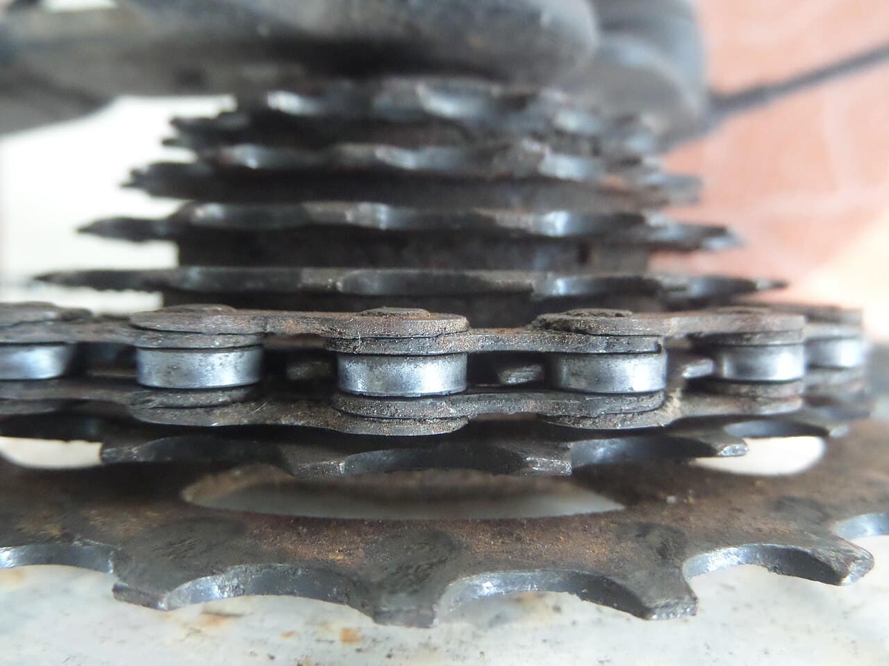 Close-up van een versleten fietsketting op de tandwielen van een cassette met roestplekken
