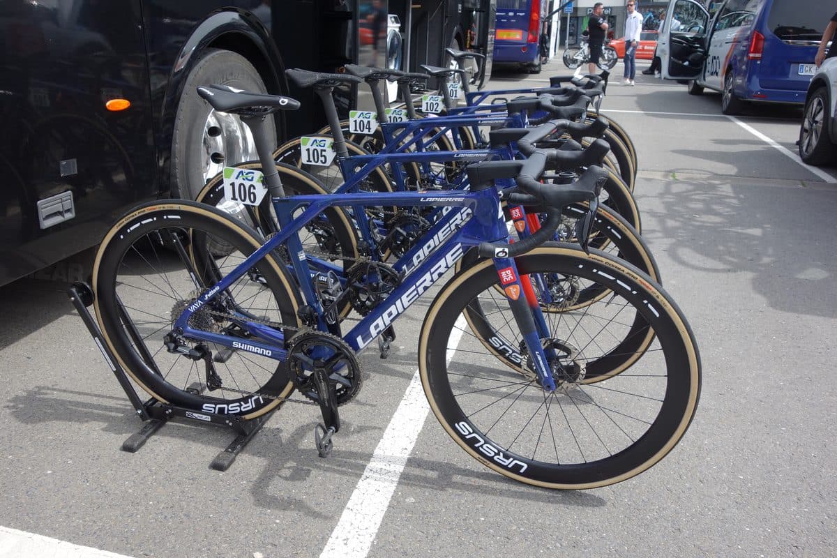 Blauwe Lapierre-racefietsen van Team Picnic PostNL met rugnummers, op een rij naast de ploegbus bij de start van Luik-Bastenaken-Luik in 2025