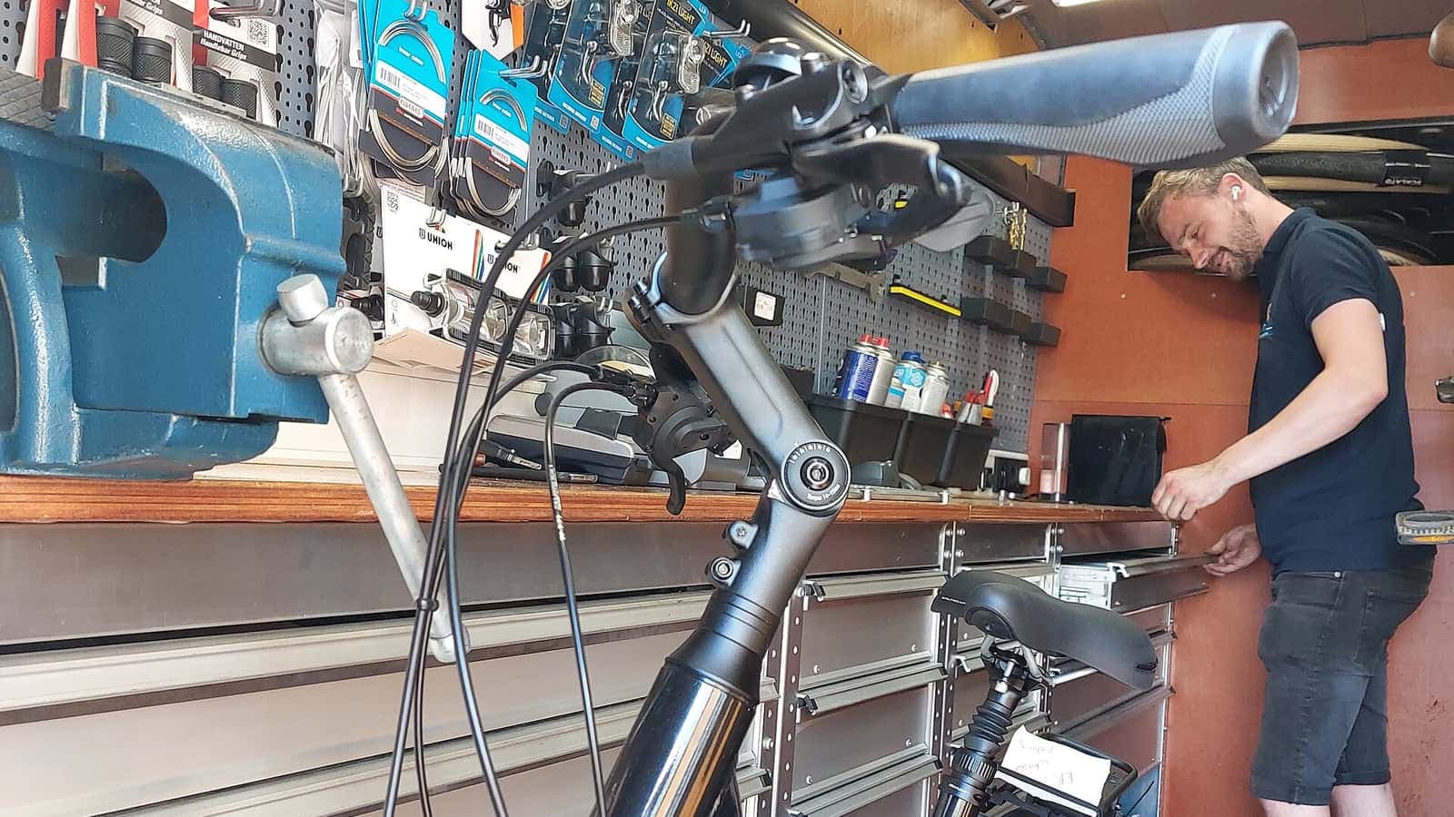 Monteur aan het werk in de bus van een mobiele fietsenmaker, met een stadsfiets en een wand met onderdelen